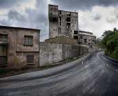 Vecchi edifici industriali trascurati con muri di pietra alterati situati lungo la strada sinuosa in una giornata nuvolosa in Spagna — Foto stock