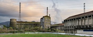 Vue grand angle de l'ancienne usine abandonnée avec des bâtiments gris minable et des tuyaux situés dans la campagne espagnole dans les Asturies — Photo de stock