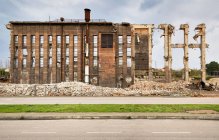 Ruines de vieilles constructions industrielles abandonnées avec des tuyaux et des tas de déchets situés près de la route contre le ciel nuageux en Espagne — Photo de stock