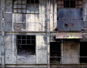 Extérieur de vieux bâtiments industriels négligés avec des murs de briques en ruine et des fenêtres endommagées avec des grilles métalliques dans les Asturies en Espagne — Photo de stock