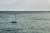 Lonely sailboat floating on calm ocean water — Stock Photo