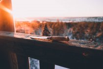Нож с деревянной ручкой на деревянном заборе против снежного леса в солнечный зимний день в сельской местности Финляндии — стоковое фото