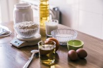 Ingredients for preparing homemade aromatic orange muffins placed on wooden counter near window in modern kitchen — Stock Photo