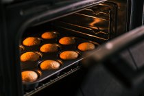 Cultivar confeiteiro irreconhecível tirando do forno deliciosos muffins caseiros na cozinha — Fotografia de Stock