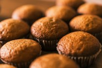 From above close up of delicious ready to eat muffin in paper case placed on wooden table in kitchen — Stock Photo