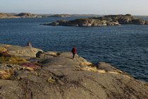 Vista posteriore di coppia anonima di turisti in capispalla casual e con zaini in piedi sulla costa rocciosa e ammirare incredibile paesaggio marino durante le vacanze — Foto stock