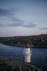 Torre di avvistamento bianca con tetto rosso e punto panoramico recintato situato sul lago vicino alle montagne grigio scuro nella giornata nuvolosa di sera — Foto stock