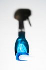 Вид сверху прозрачной бутылки с голубой мыльной жидкостью, перчатки и тени на белой поверхности — стоковое фото
