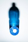 Вид зверху на прозору пляшку з блакитною мильною рідиною, що відбиває сяючі кришталеві тіні на білій поверхні — стокове фото