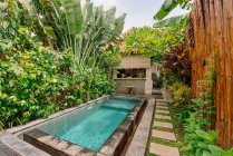 Pátio acolhedor com piscina rodeada por plantas tropicais e cerca de bambu em Bali — Fotografia de Stock