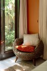 Интерьер спальни с удобным плетеным креслом с подушками — стоковое фото