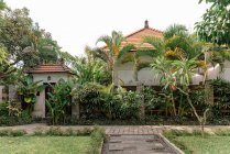 Кам'яна стежка веде до входу в будинок в оточенні екзотичних рослин в сонячний день на Балі. — стокове фото