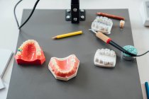From above of models of dental jaw and crowns placed on table with burnisher and pencils in modern laboratory — Stock Photo