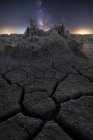 Dry cracked land with setting sun and stars in sky — Stock Photo