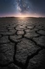 Dry cracked land with setting sun and stars in sky — Stock Photo