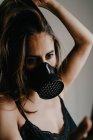 Junge Frau mit schwarzer Atemschutzmaske zur Coronavirus-Prävention steht hinter Gittern und surft Handy — Stockfoto