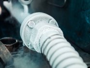 Closeup view of cooling pipe transferring liquid nitrogen surrounded by clouds of vapor on plant — Stock Photo
