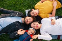 Família feliz com criança deitada na grama verde — Fotografia de Stock