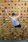 Dal soffietto irriconoscibile forte atleta maschile in abbigliamento sportivo arrampicata su parete colorata durante l'allenamento in ragazzo moderno — Foto stock