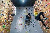 Seitenansicht einer jungen Gruppe starker männlicher und weiblicher Kletterer, die in einer modernen Turnhalle an der Wand trainieren — Stockfoto