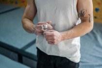 De cima de atleta masculino anônimo em pé desgaste ativo e gravando os dedos em pó de talco no ginásio — Fotografia de Stock