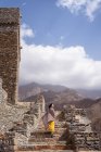 Monumentales antikes Gebäude mit abgelegenen Touristinnen, die in gelbem Kleid aus der Tür kommen, während sie den heißen, sonnigen Tag im Marmordorf Al Bahah genießen — Stockfoto