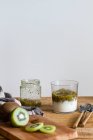 Склянка смачного здорового домашнього коктейлю з йогуртом та свіжим ківі, розміщеним на дерев'яному столі — стокове фото