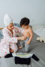 Mulher alegre em roupão de banho vestir-se pequeno filho enquanto brincam juntos em casa olhando um para o outro — Fotografia de Stock