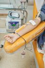 Crop anonymous female volunteer giving blood for save life in modern blood transfusion center — Stock Photo