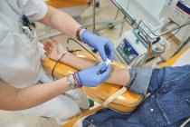 Crop especialista médico fêmea em luvas de látex realizando injeção com seringa para paciente anônimo durante procedimento de transfusão de sangue no hospital — Fotografia de Stock