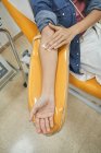 Desde arriba de la cosecha donante femenina anónima con parche en la mano sentado en silla médica después del procedimiento de transfusión de sangre - foto de stock
