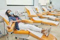 Жіночий донор з плямою на руці, сидячи в медичному кріслі після процедури переливання крові — стокове фото