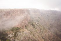 Breathtaking view of rough rocky cliffs covered in fog — Stock Photo