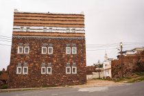 Екстер'єр житлового будинку з традиційними орнаментами на фасаді, розташованому поблизу віддаленої людини на сірий день на міській вулиці — стокове фото