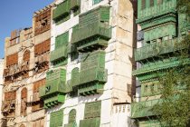 Ángulo bajo de edificios de piedra antiguos con paredes de cangrejo y balcones en la calle de la ciudad de Jeddah en Arabia Saudí. - foto de stock