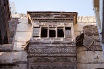 Ángulo bajo de edificios de piedra antiguos con paredes de cangrejo y balcones en la calle de la ciudad de Jeddah en Arabia Saudí. - foto de stock