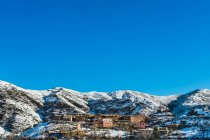 Case residenziali su pendio di montagna coperto di neve e cielo blu — Foto stock