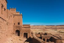 Magnificent scene with facade of ancient clay buildings and walls in Ait Ben Haddou, distant mountains and blue sky — Stock Photo