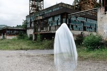 Fantôme transparent près de vieux bâtiments miniers abandonnés avec des constructions métalliques rouillées et des murs minables — Photo de stock