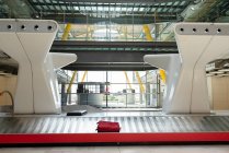 Internationaler Flughafen mit Metallbereich für die Gepäckausgabe und massiven Konstruktionen im futuristischen Stil, die von Sonnenlicht beleuchtet werden — Stockfoto