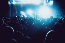 Rückansicht Silhouetten von Menschen gegen Beleuchtung mit Lichtern Bühne während der Musik-Performance — Stockfoto