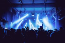 Visão traseira silhuetas de pessoas contra iluminado com luzes palco durante a performance musical — Fotografia de Stock