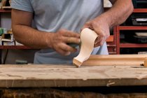 Artisan polishing wooden detail using sandpaper in carpentry workshop — Stock Photo