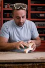 Artisan polissage détail en bois à l'aide de papier de verre dans l'atelier de menuiserie — Photo de stock