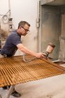 Ремесленник наносит лак на древесину жалюзи с помощью аэрографии в столярной мастерской — стоковое фото