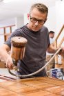 Artisan appliquant du vernis sur jalousie en bois à l'aide d'aérographe en atelier de menuiserie — Photo de stock