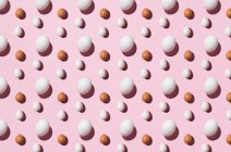 Seamless background of brown and white eggs on pink surface — Stock Photo