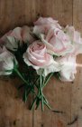 Top view of bunch of fresh pink roses placed on shabby wooden table in light room — Stock Photo