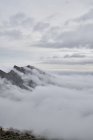 Amazing view of mountain peaks covered with fog and clouds — Stock Photo