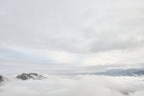 Increíble vista de los picos de montaña cubiertos de niebla y nubes - foto de stock